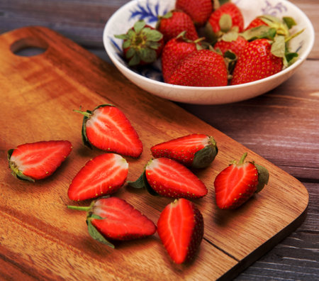 ripe strawberries in a ceramic bowl on a wooden backgroundの写真素材