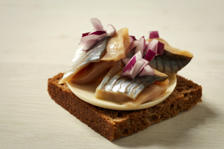 a salted herring and finely chopped red onions atop a dark rye breadの写真素材
