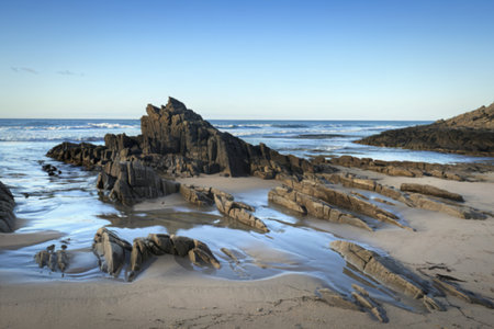 A serene beach scene with jagged rock formations