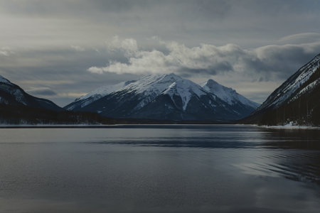 a big calm lake between the mountains covered with snow.