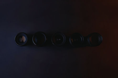 A row of five black camera lenses on a dark background with blue and red gradient