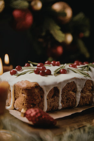 a close-up of a christmas dessert with white icing and red berries on top, sitting on a table with a...