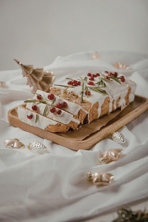 a christmas cake with white frosting and red berries on a wooden board