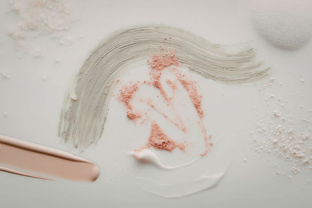 The image displays various cosmetic products on a white surface, including a green cream, a white...
