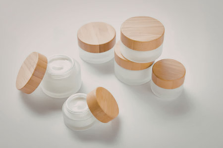 The image features a collection of small, clear glass jars with wooden lids, arranged on a plain white surface. The jars vary in size and are positioned in a way that showcases their transparent bodies and natural wood caps.の写真素材