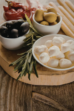 An Italian-inspired appetizer board featuring mozzarella balls, olives, pepperoncini, and...