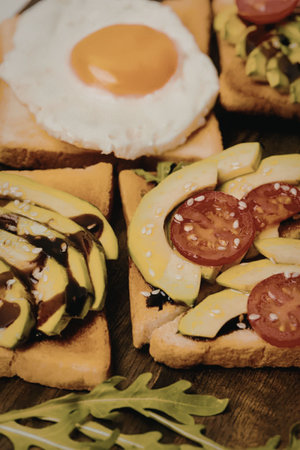 A close-up of toast slices topped with fried egg, avocado, and cherry tomatoes