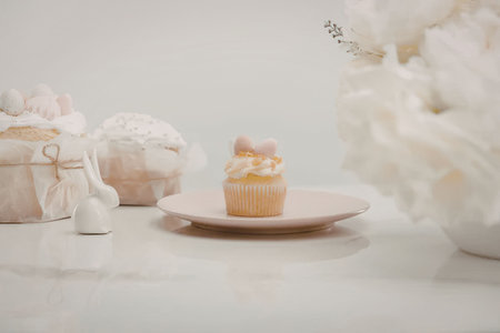 A small cupcake with buttercream frosting and pink decorations on a pink plate, accompanied by other...