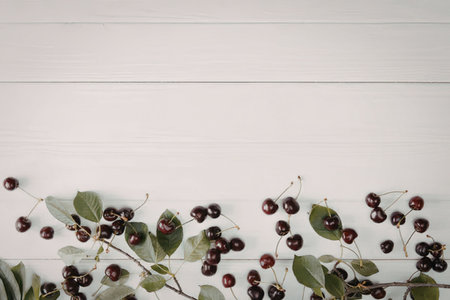 A collection of dark purple berries with green leaves on a white wooden background