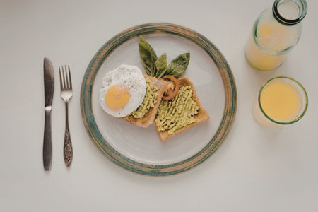 A plate with avocado toast, a fried egg, and a side of orange juice