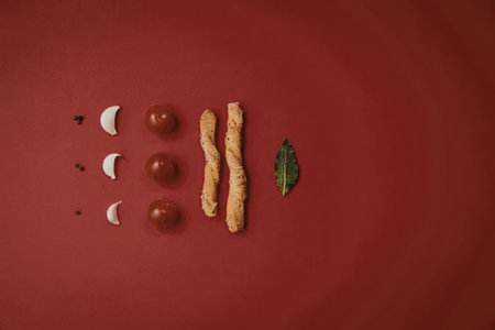 a red background with tomatoes, breadsticks and basil leafの写真素材