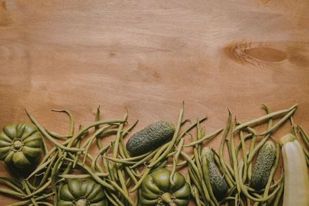 A selection of fresh green vegetables, including cucumbers, arranged on a wooden surface.