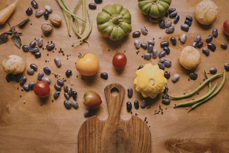 A wooden cutting board with various fresh vegetables and fruits, including tomatoes, peppers,...