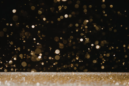 A dark background with gold glitter and bokeh effect, featuring a white and gold glittery strip at the bottom.の写真素材