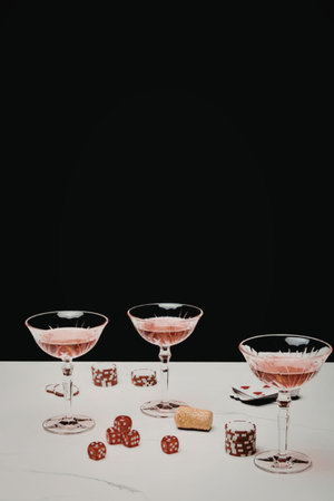 Three glasses of pink cocktail on a white table with poker chips and diceの写真素材