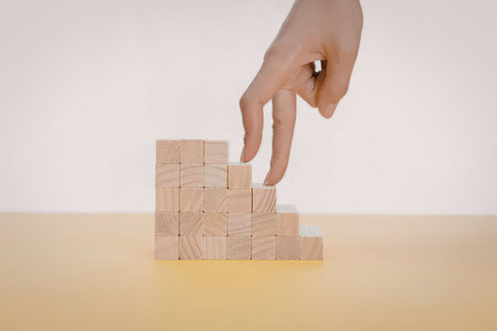 A hand placing a block on top of a stack of wooden blocksの写真素材