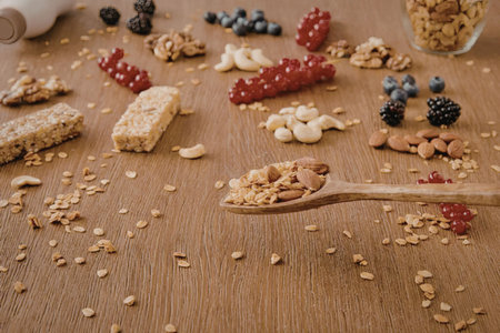 A wooden spoon with granola and various nuts and fruits on a wooden table