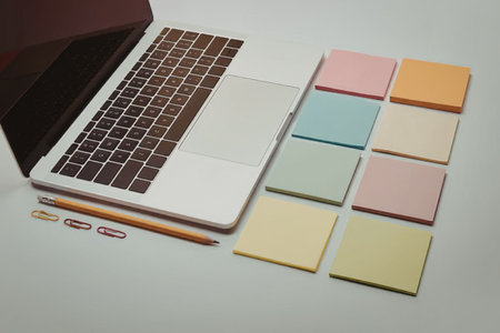 A laptop with sticky notes and a pencil on a table