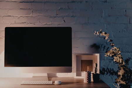 A modern home workspace setup with a large screen monitor, keyboard, and decorative items on a...