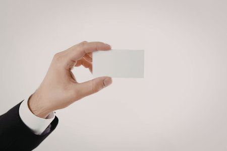 A hand in a business suit holding a blank white business card on a plain white background.の写真素材