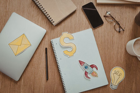 A wooden desk with a laptop, notebooks, phone, and stationery with startup and business related...