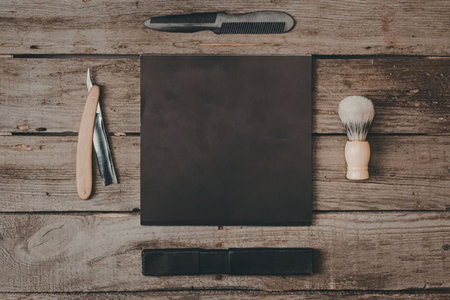 A shaving kit consisting of a razor, shaving brush, and leather strop on a wooden table.の写真素材