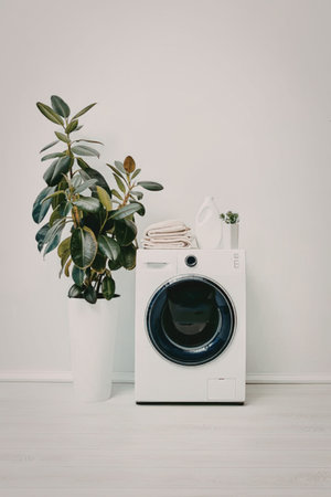 A washing machine with a plant and laundry items on top