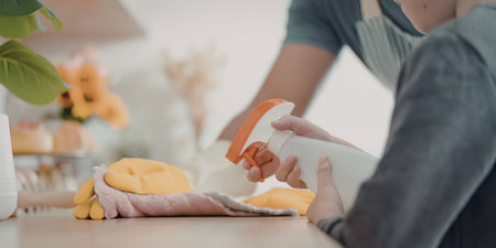 A person cleaning a kitchen countertop with a spray bottleの写真素材