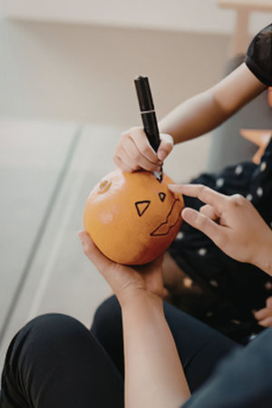 A person drawing face on pumpkin