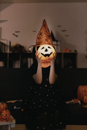 A person wearing a halloween costume and holding a pumpkin
