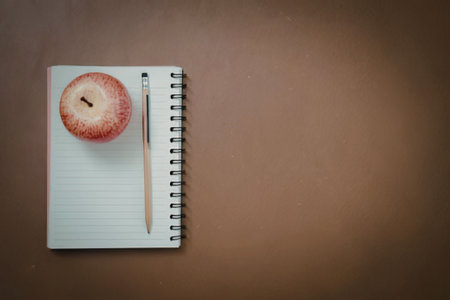 A spiral notebook with an apple and pencil