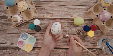 Hands decorating easter eggs with paint