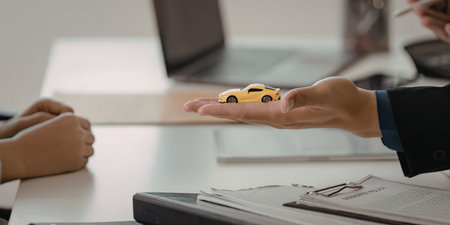 Person handing over toy car on desk