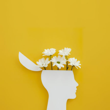 a white silhouette of a human head with flowers growing out of it on a yellow background. the flowers are white and appear to be daisies. the head is in profile, facing to the right. the background is a solid yellow color.