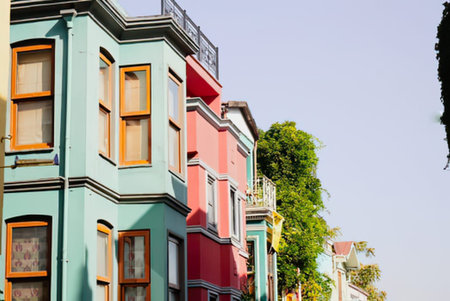 Brightly painted residential buildings lined up along a street under clear skies.
