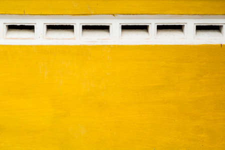 Yellow walls of an old building with vents white.の写真素材