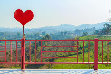 Red heart and pink fence behind mountainの写真素材