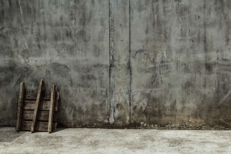 The old wall is made of cement, with a plank leaning against the wall.の写真素材