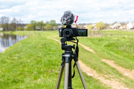 Digital camera with microphone on a tripod close-up. Mirrorless digital camera and microphone recording while broadcasting in nature.の写真素材