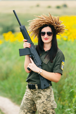 Female soldier in military uniform. A girl in a military uniform with a weapon. Ukrainian woman in a wreath.の写真素材