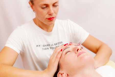 Beautician massaging woman's face. Attractive girl having facial treatment and massage. The young woman is lying and relaxing.の写真素材
