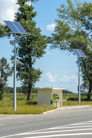 Lamp post with solar panel system on road with blue sky and trees. Autonomous street lighting using solar panels. Street lamp, on batteries from the sun. Alternative renewable energy systems.の写真素材