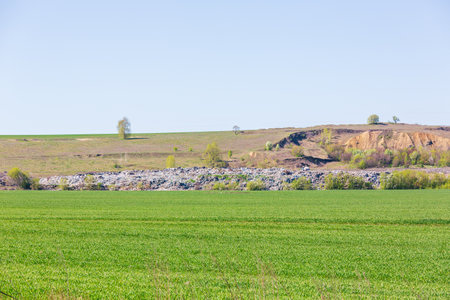 A view of the landfill. Garbage dump. A pile of plastic rubbish, food waste and other rubbish. Pollution concept. A sea of garbage starts to invade and destroy a beautiful countryside scenery.の写真素材