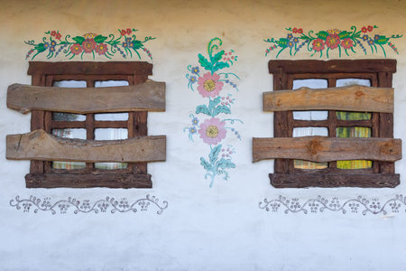 The windows of the house are boarded up. An old abandoned Ukrainian house with boarded up windows. Ukrainian house of the 19th century. The facade of the building is made in the Ukrainian folk style of a village houseの写真素材
