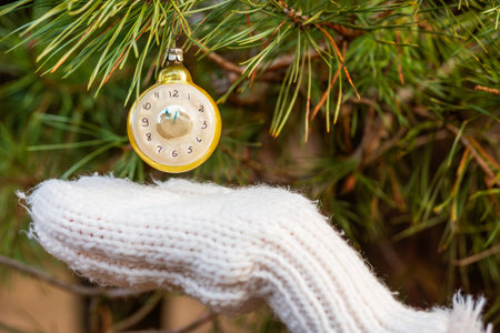 Old New Year's toy in the form of a clock on a Christmas tree close-up. Five minutes before the New Year. Christmas background with decorations.の写真素材