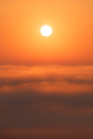 Warm dawn above the clouds. The moment of sunrise, which rises above the clouds, immersing...