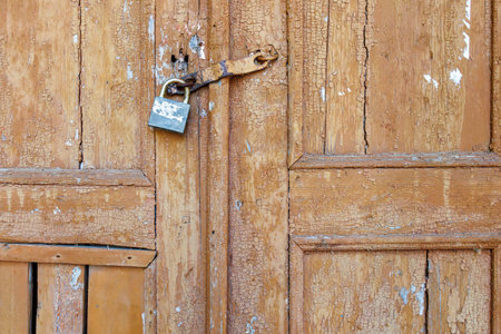 Old wooden door with rusty metal padlock close up.