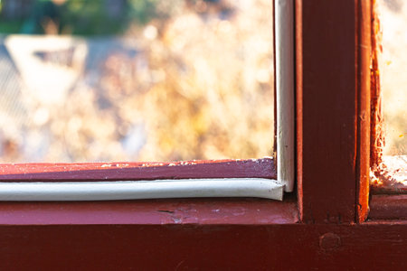 Insulation tape taped to an old wooden window frame to seal and weatherproof it shows a close-up of...