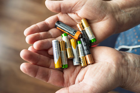 Hands holding a pile of AA and AAA batteries, close-up. A combination of used and new batteries in different colors, symbolizing energy storage and energy sources.の写真素材