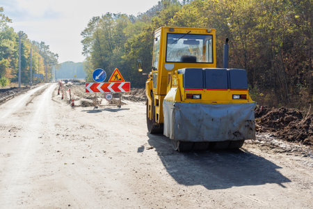 A yellow machine parked on the road. Machine for laying asphalt during road repair or construction. Road repair works on an asphalt surface. Laying new asphalt.の写真素材